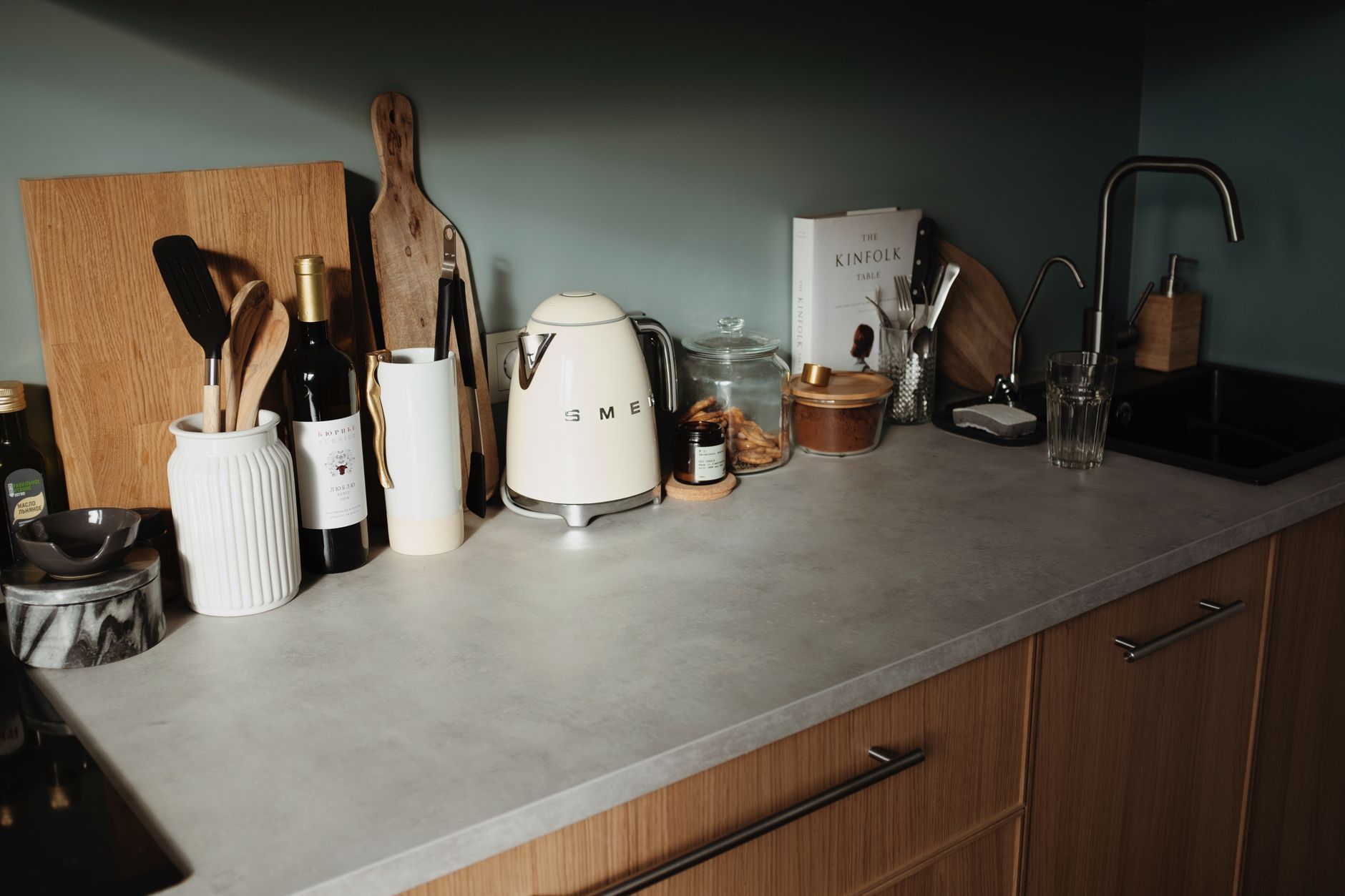 A butcher block slab on a kitchen counter holding a kettle, scale and mug