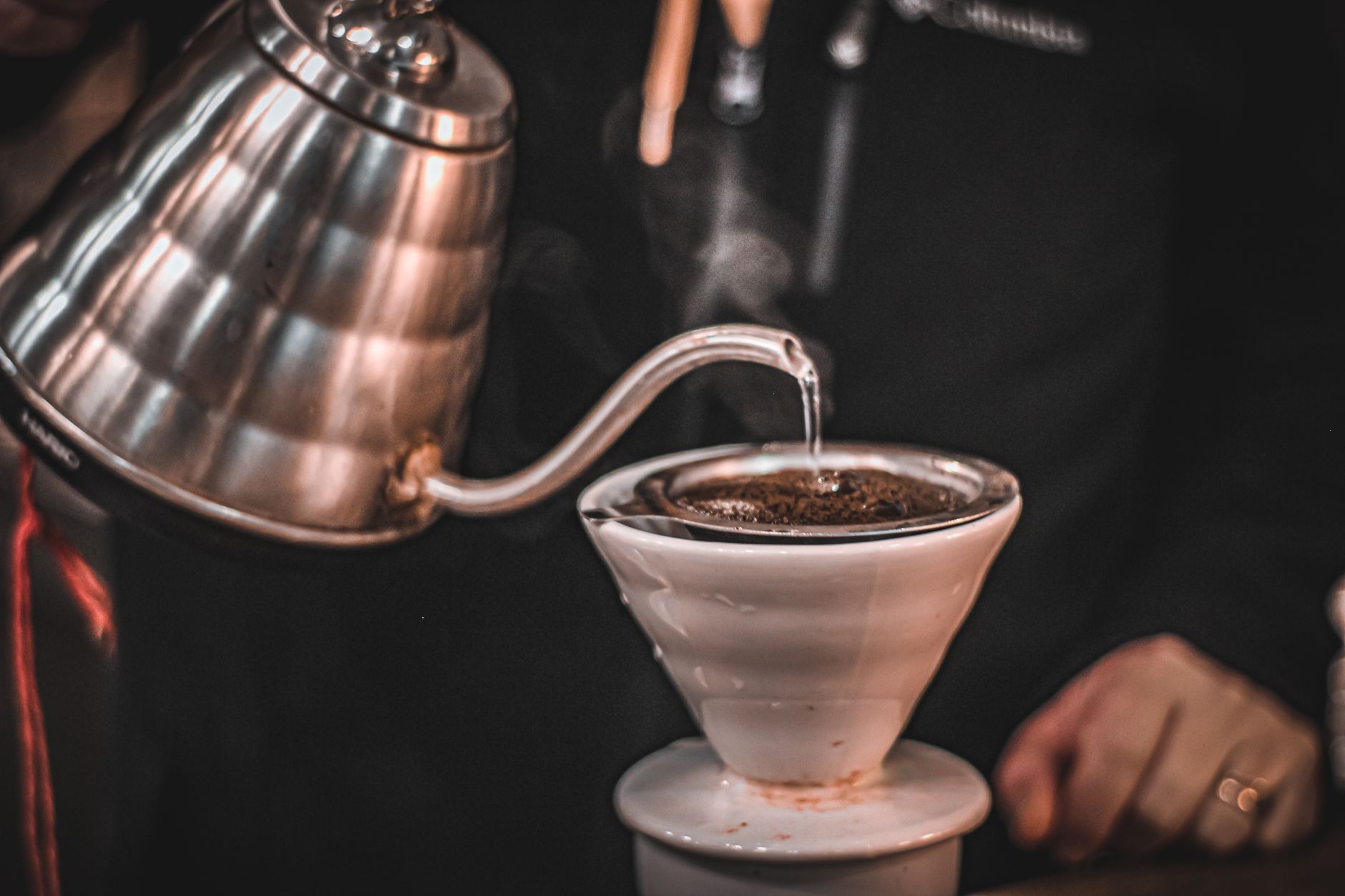 Gooseneck kettle pouring water in a slow spiral over a paper filter cone